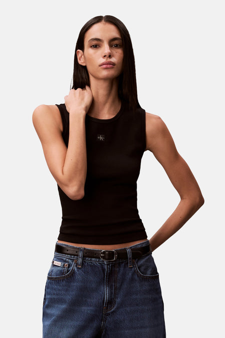 Débardeur noir Calvin Klein, avec texture côtelée et un jean avec ceinture.