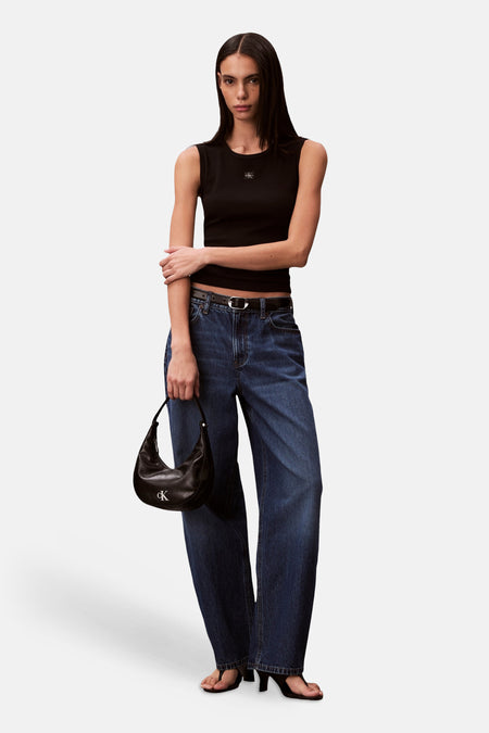 Haut noire Calvin Klein, portée avec un jean ample et un petit sac à main noir.