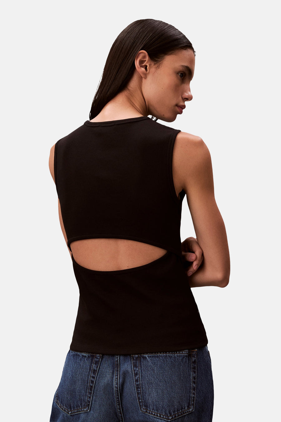 Haut noire Calvin Klein avec découpe au dos, portée avec un jean délavé foncé.