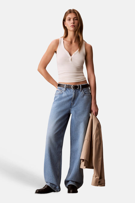 Jean en denim bleu clair coupe spéciale de Calvin Klein, porté par un mannequin avec un débardeur blanc et une ceinture noire.