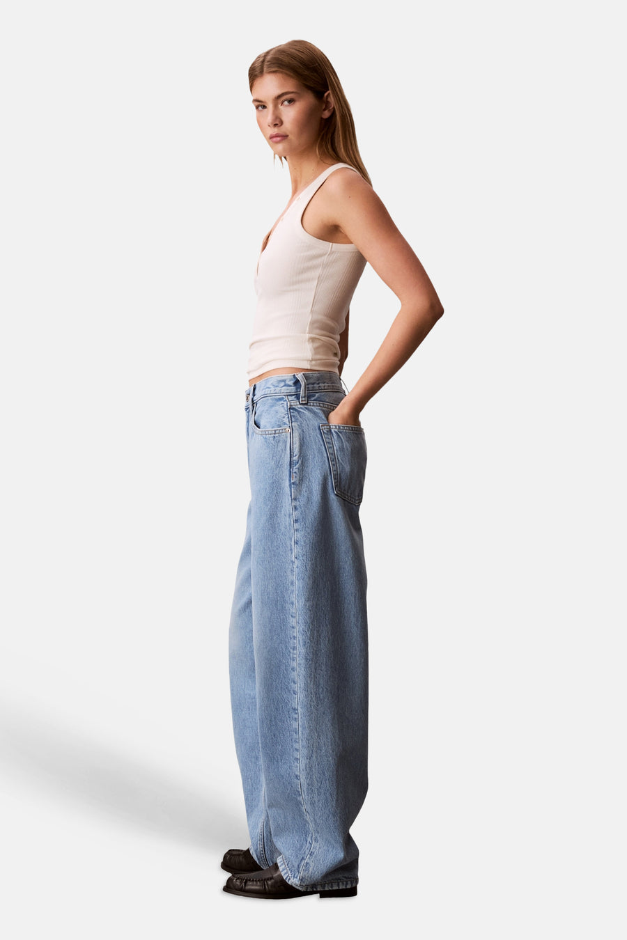 Jean en denim bleu clair coupe spéciale de Calvin Klein, à jambes larges, porté par un mannequin les mains dans les poches.