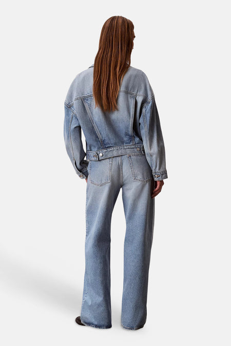 Lichtblauwe wijde jeans van denim van Calvin Klein, gedragen door een model en gecombineerd met een bijpassend spijkerjack, gezien vanaf de achterkant.