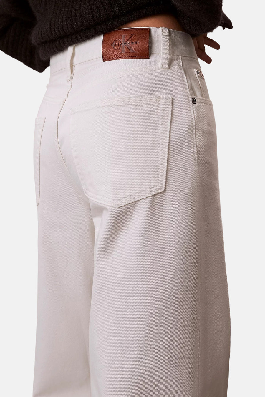 Witte wide-leg jeans van off-white denim van Calvin Klein, met bruine leren logopatch en opgestikte achterzakken.