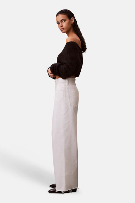 Jean large en denim blanc cassé de Calvin Klein avec ourlet brut, porté par un mannequin de profil.