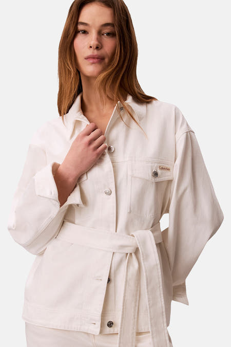 Korte off-white denim jas van Calvin Klein, met lange mouwen en een riem in dezelfde stof.
