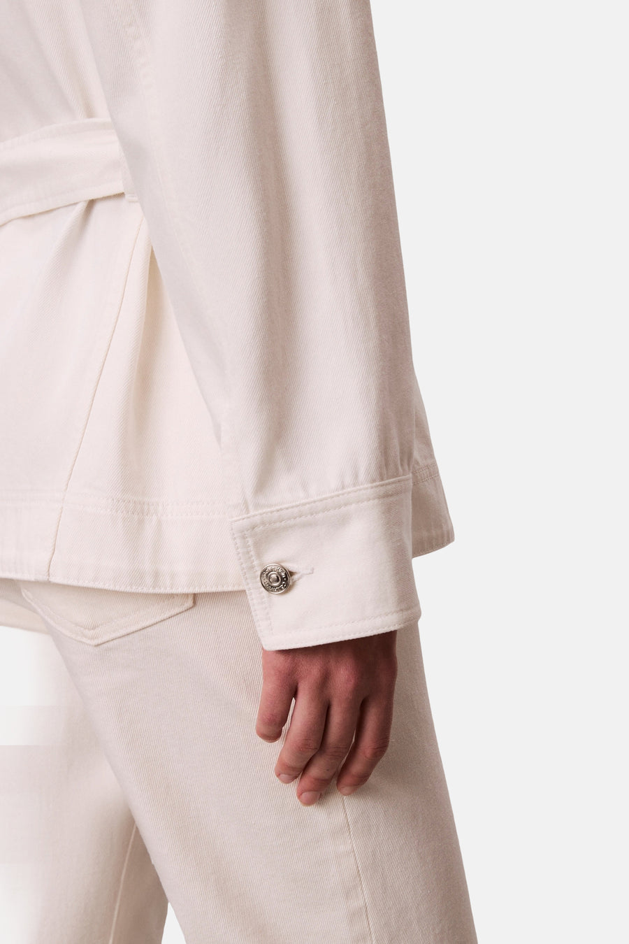 Veste courte en denim blanc cassé de Calvin Klein, avec détail de bouton argenté sur la manche, courte.