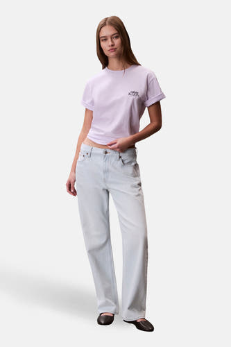 T-shirt à manches courtes violet de Calvin Klein, avec manches retroussées et un jean bleu clair.