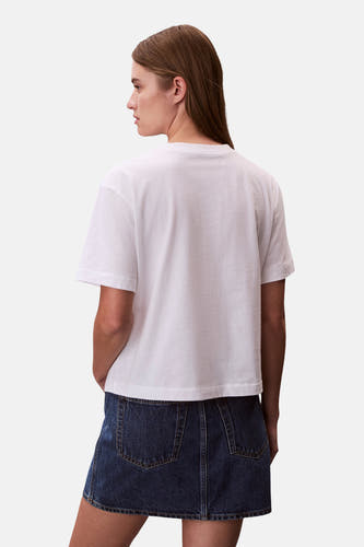 T-shirt blanc à manches courtes Calvin Klein, associé à une jupe en jean bleu foncé, vu de dos.