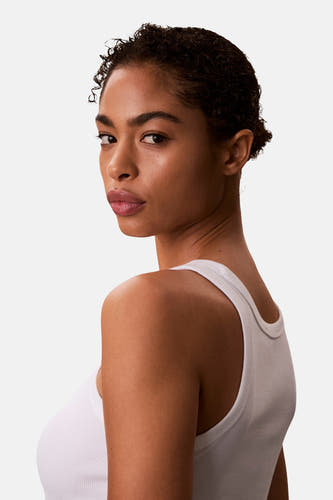 Haut blanche Calvin Klein, vue par-dessus l'épaule avec une texture côtelée et un débardeur blanc.