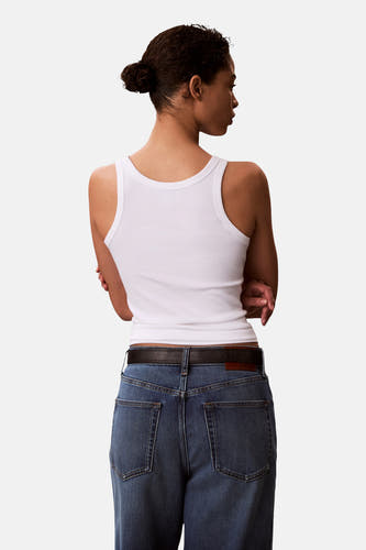 Haut blanche Calvin Klein, vue de dos avec une texture côtelée et associée à un jean et une ceinture.
