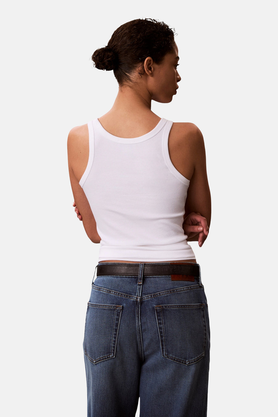 Haut blanche Calvin Klein, vue de dos avec une texture côtelée et associée à un jean et une ceinture.