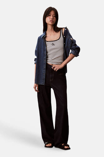 Haut à manches courtes à rayures de Calvin Klein, porté avec une chemise en jean et un jean ample foncé.