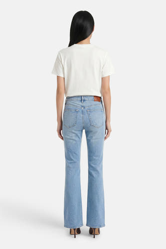 Lichtblauwe skinny bootcut jeans van Calvin Klein, achterzijde met bruin label, model draagt wit T-shirt en hoge hakken