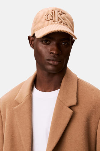 Manteau brun Calvin Klein avec texture corduroy et logo CK sur la poitrine.