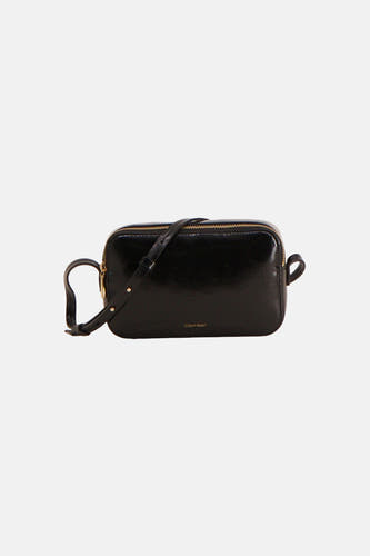 Sac à bandoulière rectangulaire noir de Calvin Klein, en matière brillante aspect cuir légèrement grainé avec des passants sur les côtés.