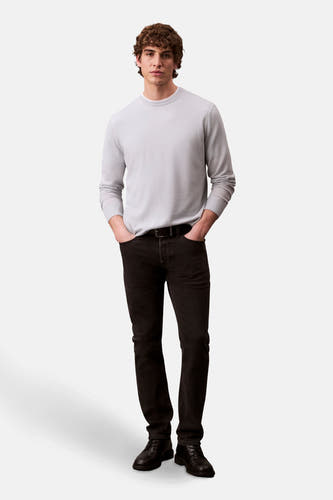 Jean slim fit noir de Calvin Klein, porté avec une chemise grise claire et des chaussures noires.