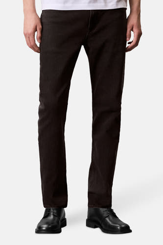 Boutons de jeans Calvin Klein en denim gris foncé, avec un design simple et des chaussures noires.
