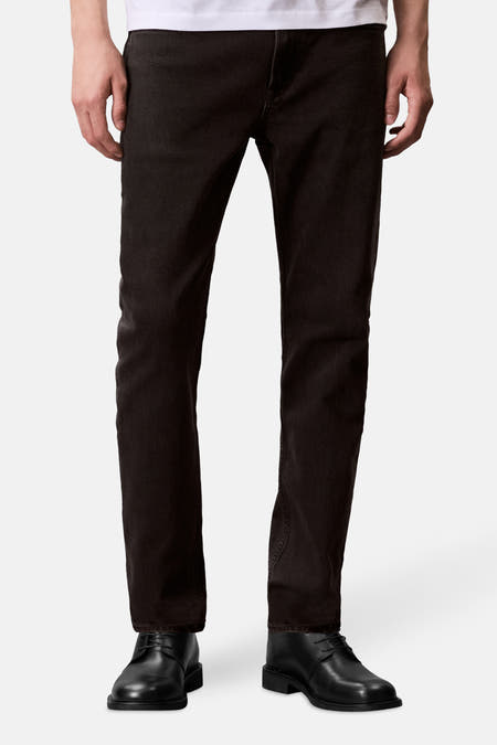 Boutons de jeans Calvin Klein en denim gris foncé, avec un design simple et des chaussures noires.