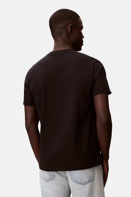 T-shirt noir à manches courtes de Calvin Klein, porté par un mannequin de dos avec un jean clair.