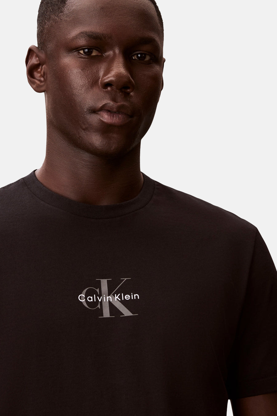 T-shirt noir à manches courtes Calvin Klein avec logo CK gris et texte sur la poitrine.