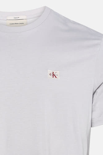 Grijze korte mouw t-shirt van Calvin Klein met klein wit logo met rode CK letters op borst, close-up voorzijde