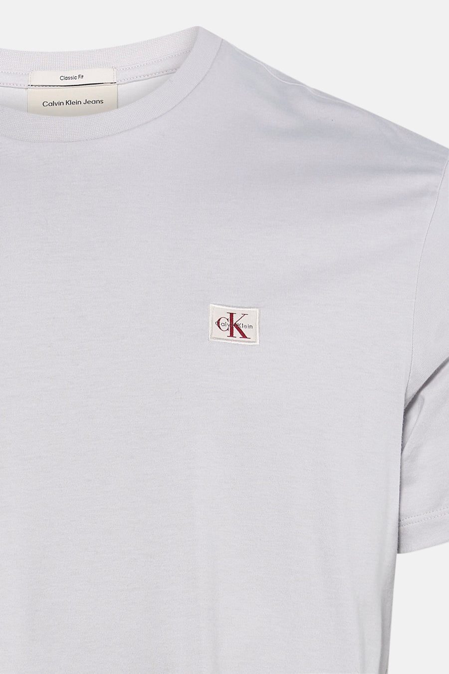 Grijze korte mouw t-shirt van Calvin Klein met klein wit logo met rode CK letters op borst, close-up voorzijde