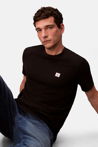 T-shirt noir à manches courtes de Calvin Klein, avec un logo sur la poitrine, porté avec un jean bleu.