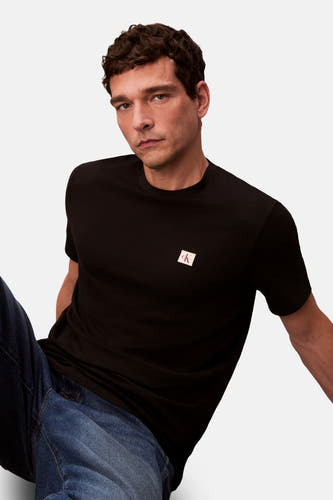 T-shirt noir à manches courtes de Calvin Klein, porté avec un pantalon de travail dans une pose décontractée.
