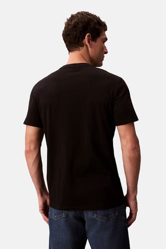 T-shirt noir à manches courtes de Calvin Klein, vu de derrière, porté avec un pantalon de travail.