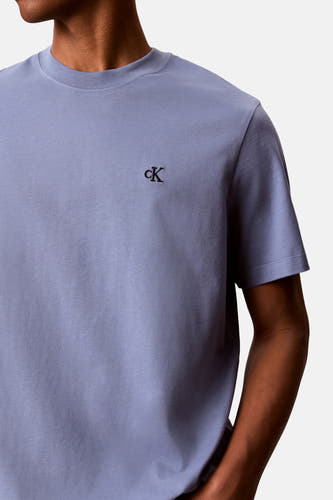 Blauw T-shirt van Calvin Klein met geborduurd cK-logo op de borst, gedragen door een persoon.