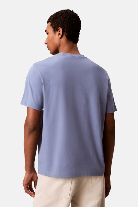T-shirt à manches courtes bleu clair Calvin Klein, porté par un homme, vue de dos, avec un pantalon beige.