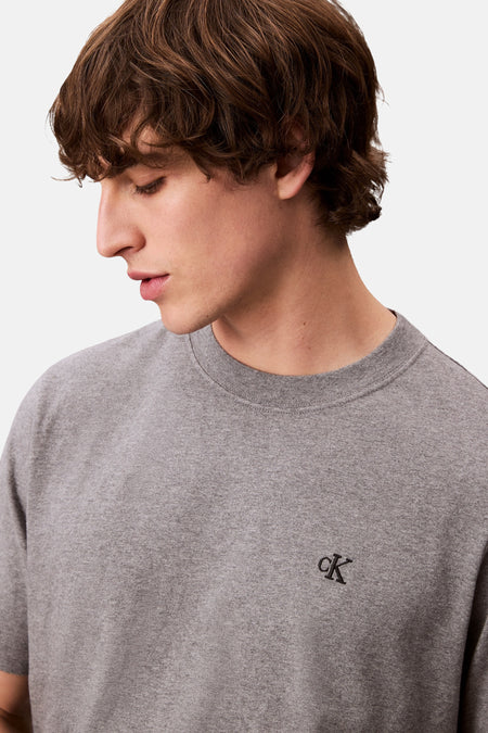 T-shirt gris à manches courtes de Calvin Klein, avec un petit logo de marque sur la poitrine.