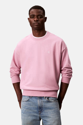 Pull-over rose Calvin Klein avec un petit logo CK et porté avec une pantalon en cuir.