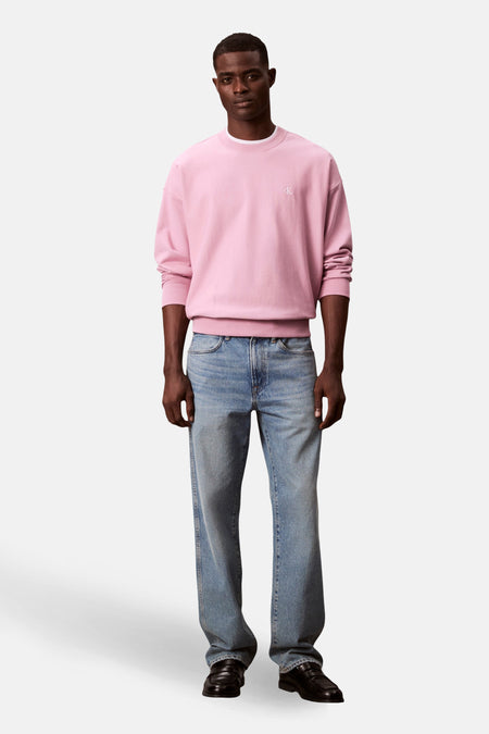Man in roze sweatshirt en blauwe jeans.