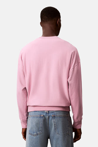 Pull-over rose de Calvin Klein, vu de de l'ar avec avec des jeans bleus.