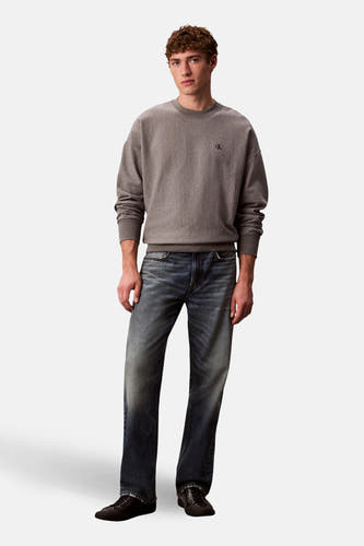Grijze sweater met ronde hals van Calvin Klein, gedragen met donkere jeans en zwarte schoenen.