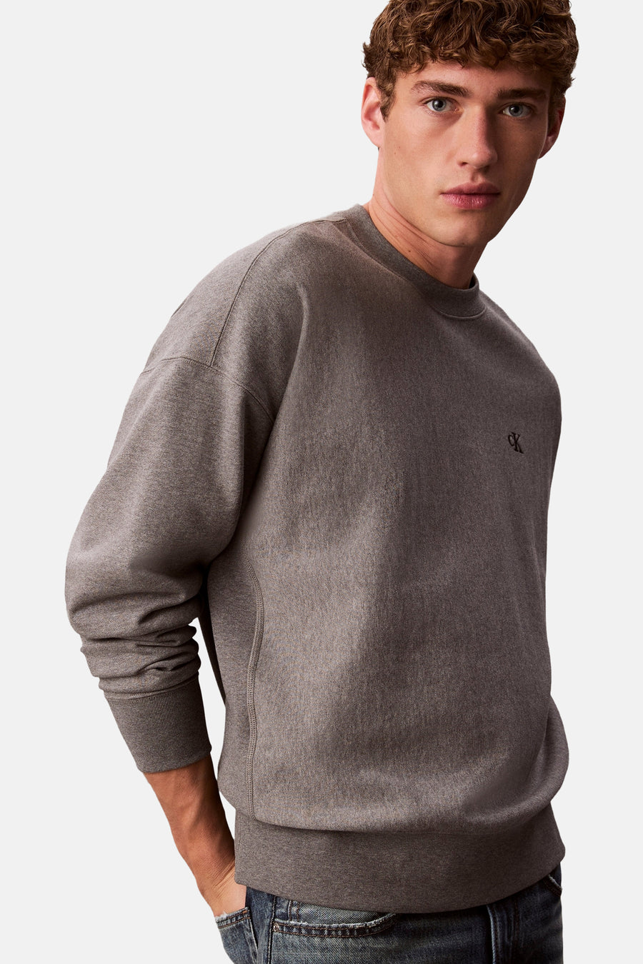 Grijze Calvin Klein sweater, mannelijk model, casual pose.