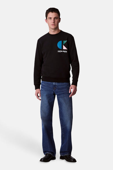 Pull noir de Calvin Klein, vu de derrière avec avec jeans bleu marine et des chaussures noires.