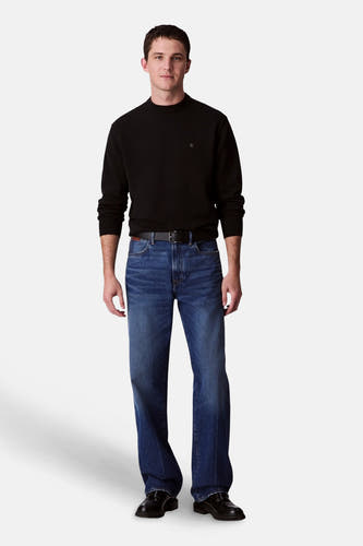 Pull-over noir de Calvin Klein, porté avec des jeans bleus à jambe droite et une ceinture en cuir noire.