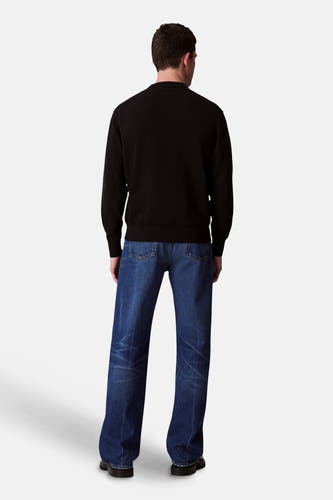 Pull-over noir avec col rond de Calvin Klein, vu de derrière, associé à des jeans foncés.