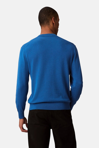 Pull-over bleu avec col rond de Calvin Klein, vu de derrière, associé à un pantalon noir.