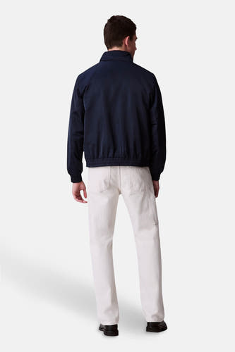 Veste de pluie bleue Calvin Klein, vue de dos, avec un short léger et des chaussures noires.
