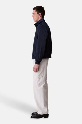 Veste de pluie bleue Calvin Klein, présentée en vue latérale, associée à des pantalons légers et des chaussures noires.
