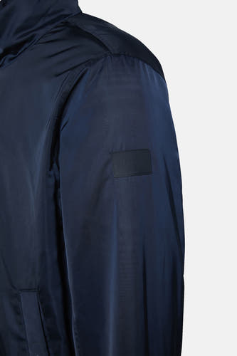 Veste de pluie bleue Calvin Klein avec des manches longues et un patch logo de la marque.
