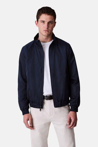 Veste de pluie bleue Calvin Klein portée sur un t-shirt blanc et une légère avec pantalon ceinture.