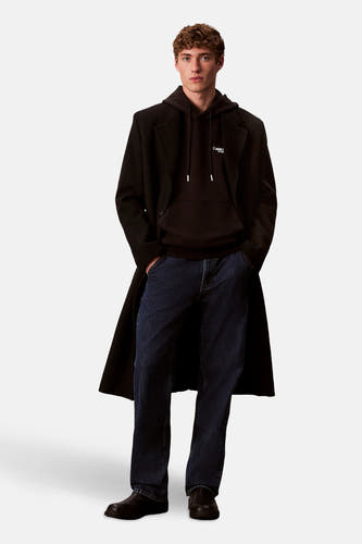 Pull-over noir de Calvin Klein, porté sous un long manteau noir et des jeans foncés.