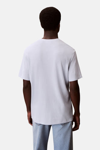 T-shirt bleu à manches courtes de Calvin Klein, dos visible, avec un motif à carreaux, porté avec un jeans bleu.