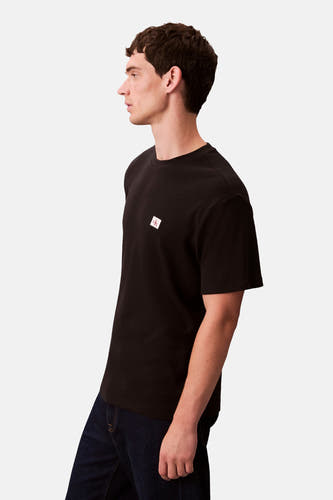 Zwart T-shirt met korte mouwen van Calvin Klein, met een klein logo op de borst en gedragen met donkere jeans.
