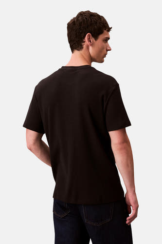 T-shirt noir à manches courtes de Calvin Klein, texture lisse, dos d'un modèle avec des jeans.