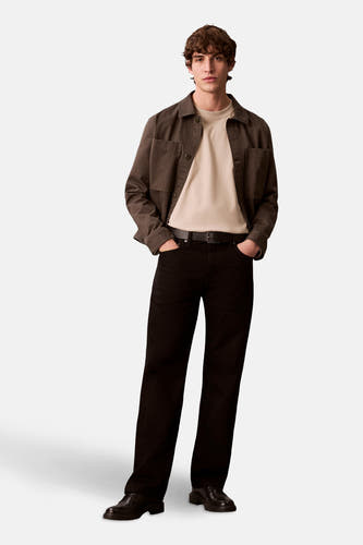 T-shirt beige à manches longues de Calvin Klein, porté sous un blouson marron avec des pantalons noirs et des chaussures.